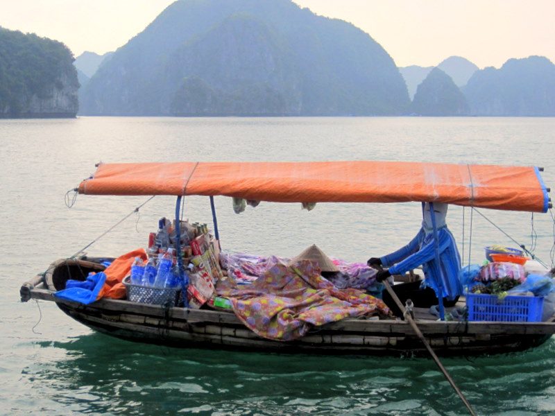 A woman selling goods from a boat in Ha Long Bay, Vietnam.