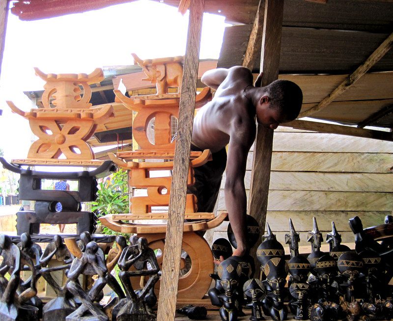 A man reaching for wooden figurines in Ghana.