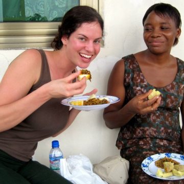 Scarfing delicious food in Ghana as Millicent chuckles.
