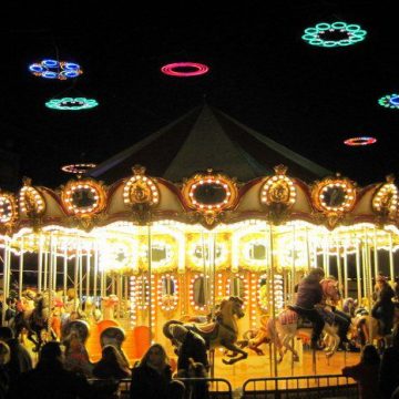 The carousel in Madrid's Plaza Mayor spins gold under rainbow circle lights for the holidays!