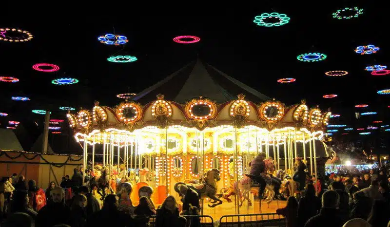 The carousel in Madrid's Plaza Mayor spins gold under rainbow circle lights for the holidays!