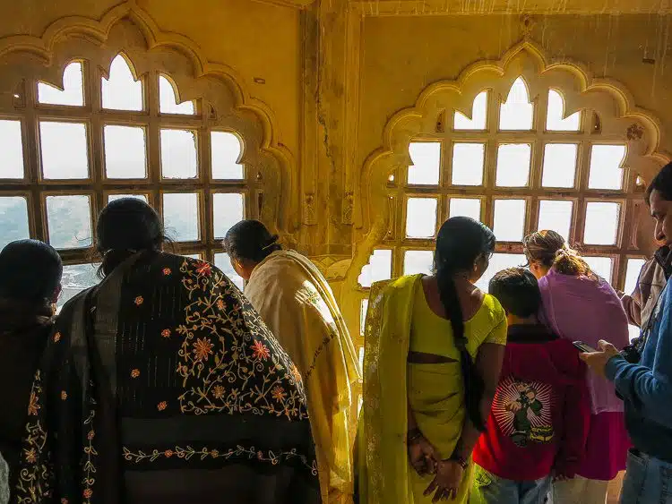 Women in saris looking out of a palace window. 