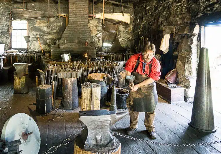 Old Sturbridge Village Blacksmith getting ready to hammer on an anvil.